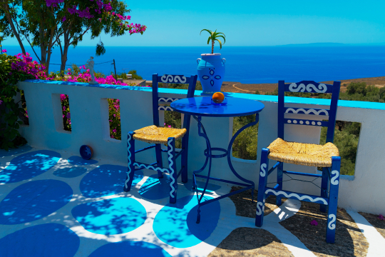 Zwei blaue Stühle an einem Tisch mit Blick über das Meer